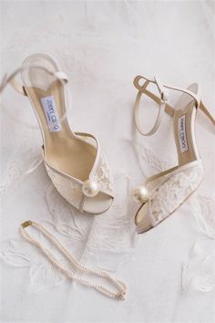 a pair of shoes and a necklace on a white cloth with lace, beads and pearls