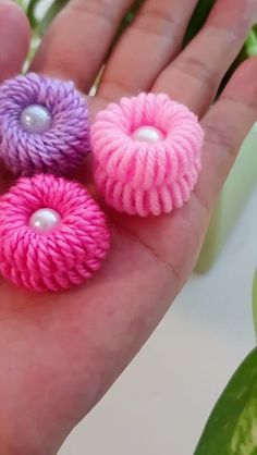 three pink, purple and white flowers with pearls in the middle on a person's palm