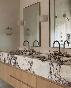 a bathroom with marble counter tops and double sinks in it's own area, along with two mirrors on the wall