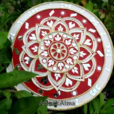 a red and white plate sitting on top of some green leaves in front of trees