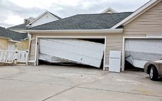 a car is parked in front of a house that has been knocked over by the wind