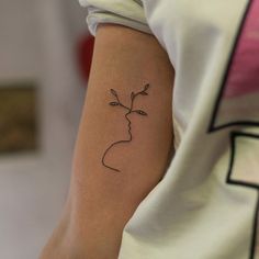 a woman's arm with a small flower tattoo on the left side of her arm