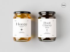 two jars of honey sitting next to each other on a white surface with the label black cherry