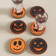 four halloween coasters with jack - o'- lantern faces on them and one drink in the middle