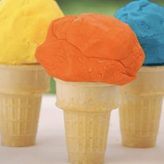 three ice cream cones with different colored toppings on top of each cone, sitting on a table