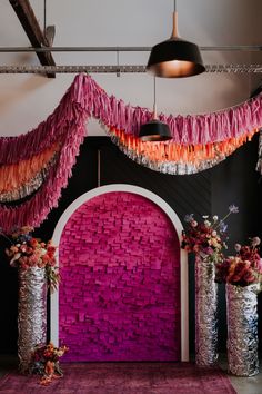 a decorated stage with pink and orange decorations on the wall, flowers in vases next to it