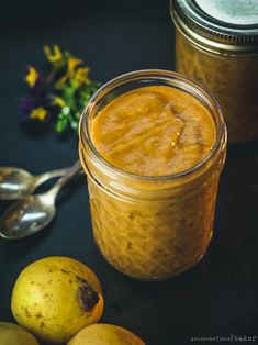 a jar filled with yellow liquid next to some pears