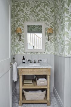 a white sink sitting under a bathroom mirror next to a wooden vanity with two baskets underneath it