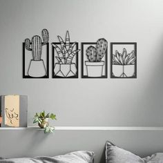 three black and white pictures hanging on the wall above a bed with a pillow, potted plants and a cardboard box