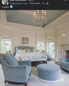 a bedroom with blue furniture and chandelier hanging from the ceiling in front of a large bed