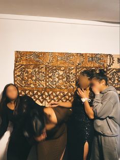 three women are standing in front of a wall hanging on the wall and touching each other's hands