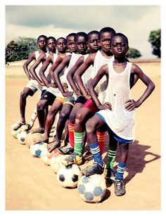 a group of young men standing next to each other on top of soccer balls