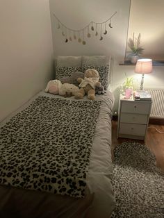 a teddy bear sitting on top of a bed in a room with white walls and wooden floors