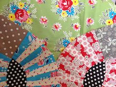 an assortment of different colored fabrics on display in a store window, with flowers and polka dots