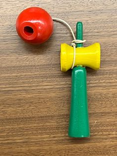 a wooden table topped with a toy bell and a red ball on top of it