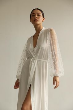 Our long bridal silk robe with wide long sheer sleeves with pearls. The robe is both casual and elegant, you may wear it on the hen party or spontaneously around your home on a daily basis. It is also an amazing outfit for your vocation, to wear it on the beautiful beach or by the pool as a cover up. Model is 168 cm, 84/64/89 wears size XS  Total length 135 cm  Off white color Elegant V-neck Kimono For Wedding, Elegant V-neck Wedding Kimono, Elegant Sheer Robe For Party, White Silk Wedding Nightgown, Elegant Sheer Party Kimono, Elegant Floor-length Evening Nightgown, White Satin Evening Robe, Elegant Evening Floor-length Nightgown, Sheer Long Sleeve Robe For Wedding Night