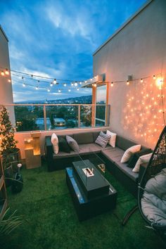 an outdoor living room with string lights on the ceiling and couches in the grass