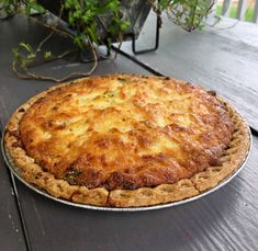 a pie sitting on top of a wooden table next to a potted green plant