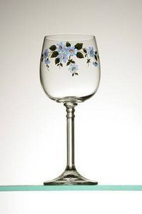 a wine glass with blue flowers painted on the side sitting on top of a shelf