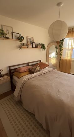 a bed sitting in a bedroom next to a window covered in curtains and pillows on top of a rug