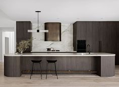 a modern kitchen with marble counter tops and dark wood cabinets, along with two bar stools