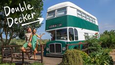 two people standing in front of a double decker bus with the words double decker on it