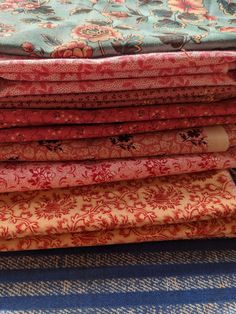 a stack of fabric sitting on top of a blue and white table cloth covered in flowers