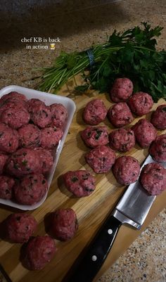 some meatballs are sitting on a cutting board next to a knife and parsley