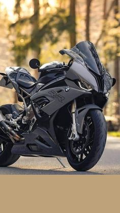 a black motorcycle is parked on the side of the road in front of some trees