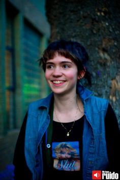 a woman standing next to a tree smiling