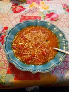 a blue bowl filled with soup on top of a colorful table cloth covered tablecloth