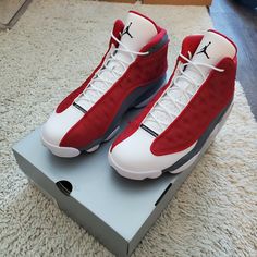 a pair of red and white air jordans on top of a shoe box in a room