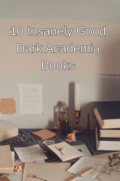 a pile of books sitting on top of a table next to a candle and other items