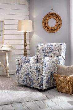 a blue and white chair sitting in a living room next to a lamp