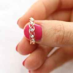 a woman's hand holding a pink ring with two diamonds on it and the middle finger