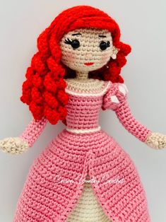 a crocheted doll with red hair wearing a pink dress