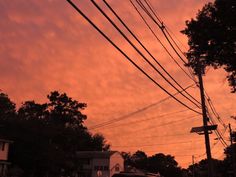 the sky is pink and orange with power lines