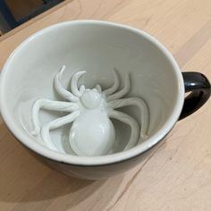 a white bowl with a spider in it on a table