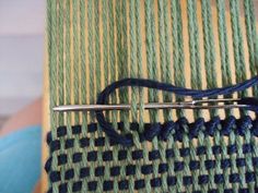 a close up of a weaving machine with blue and green yarn