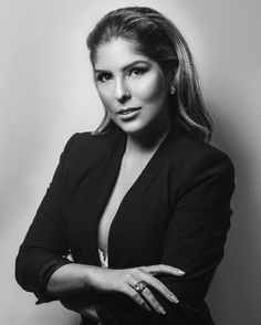 a black and white photo of a woman with her arms crossed, posing for the camera