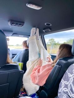 two women sitting in the back seat of a car with their feet up and one holding a cup