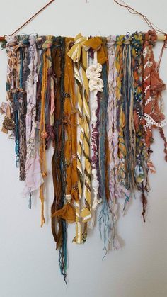 a group of scarves hanging on a wall next to a white wall with string