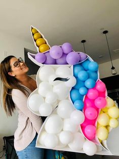 a woman standing next to a giant balloon sculpture with balloons in the shape of an unicorn