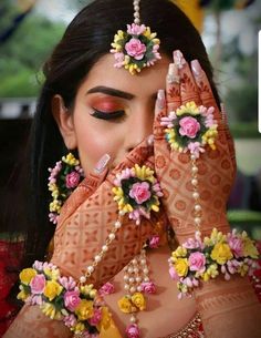 a woman with her hands on her face and some flowers around her neck, wearing an elaborate head piece