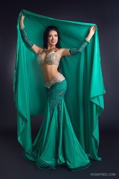 a woman in a green belly dance costume posing for the camera with her hands on her hips