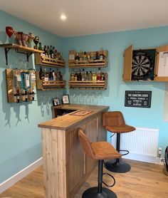 a bar with two stools in front of it and shelves on the wall behind it