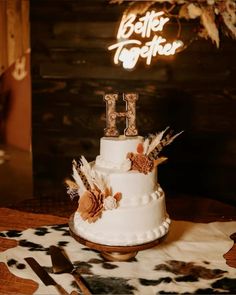 a wedding cake with feathers and the letter h on top is sitting on a table