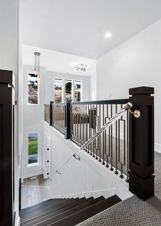 a staircase leading to the upper level of a house with white walls and wood floors