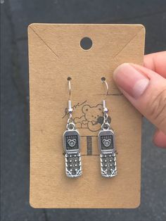 a pair of earrings is being held in front of a cardboard card that says hello kitty