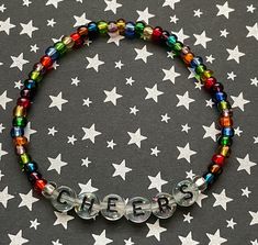 Let's toast the new year with this handmade beaded stretch bracelet that spells out CHEERS. Clear confetti sparkle filled black letter round discs are surrounded by festive multicolored glass seed beads.  The perfect accessory to ring in 2022 with!  Bracelets are available in a variety of lengths.  Pick your custom length from the drop down menu below.  All our bracelets are made with quality in mind.  With that being said, all bracelets should be treated with care while putting on, wearing, and Word Jewelry, Gift For Hostess, Preppy Bracelets, Holiday Bracelets, Beaded Memory Wire Bracelets, Preppy Christmas, Beaded Memory Wire, Nye Party